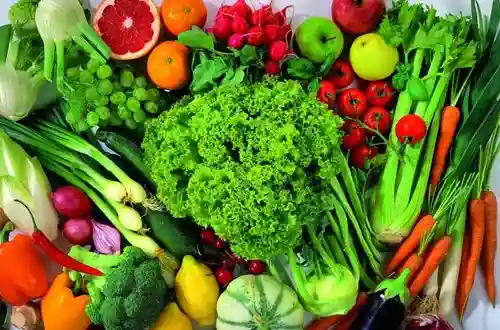 Vibrant display of fresh fruits and vegetables: lettuce, carrots, celery, grapes, apples, citrus, tomatoes, and more.