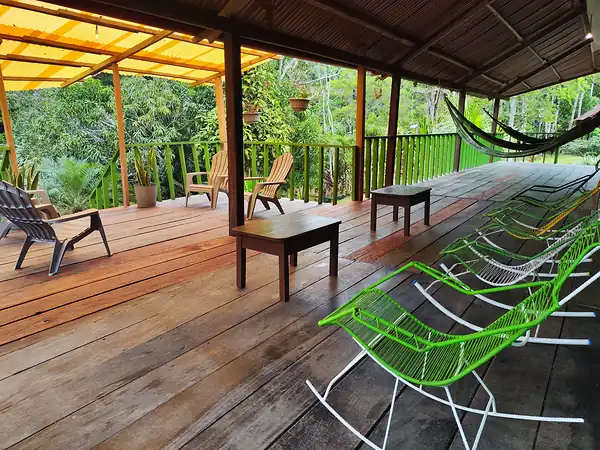 The lodge porch with wooden loungers, green rope chairs and hammocks looking out over the jungle.
