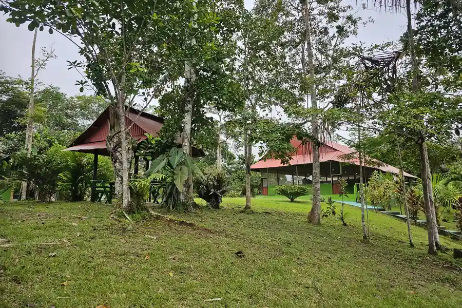 Two red-roofed buildings sit among trees on an open lawn at the retreat grounds.