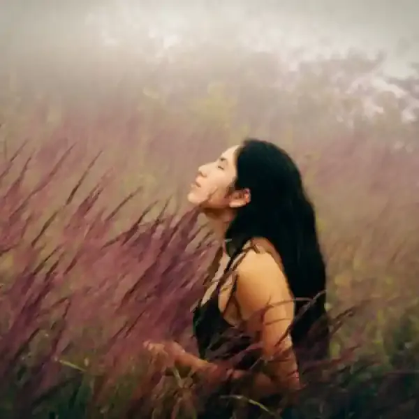 woman in foggy field of chest high golden grass